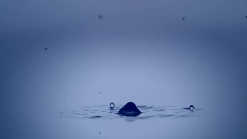 Water Droplets Create Ripples in a Blue Fluid