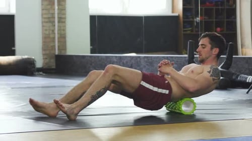 Man Using Roller for Back Exercise in Gym