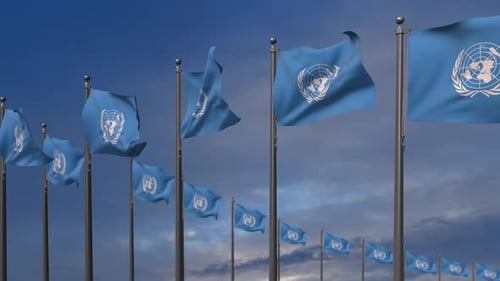 United Nations Flags Waving in Blue Sky with Clouds