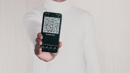 Male Hand Shows QR Code on Smartphone on White Background