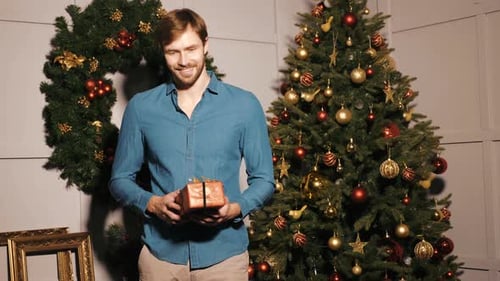Man Holding a Gift in Christmas Decorated Room