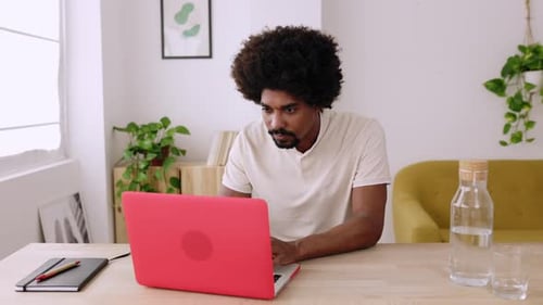 Young Adult Working on Laptop at Desk Indoors