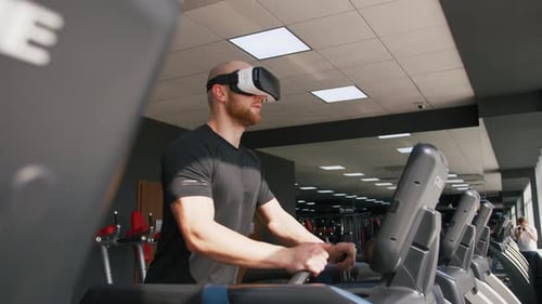 Young Strong Man Exercising on Treadmill at the Gym Wearing VR Glasses Slow Motion