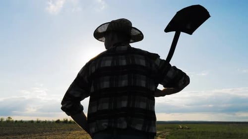 Farmer with Shovel Standing in Rural Field