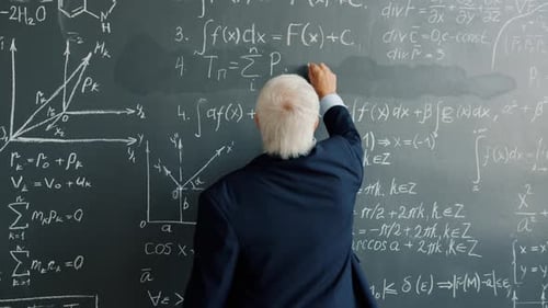 Senior Professor Writing Scientific Equations on Chalkboard