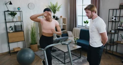 Chico en ropa deportiva apoyando con aplausos a su amiga activa y cansada en forma que corre