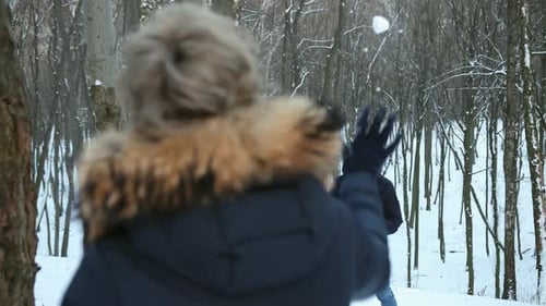 Couple Enjoying Winter Snowball Fight in Forest