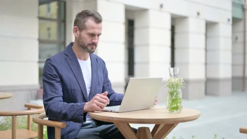 Mann trinkt Wasser während der Arbeit am Laptop im Café im Freien