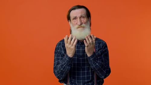 Senior Man Pleads With Hands Clasped, Orange Background