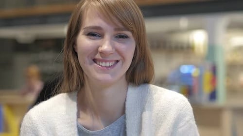 Portrait of Smiling Young Woman Looking at Camera in Cafe