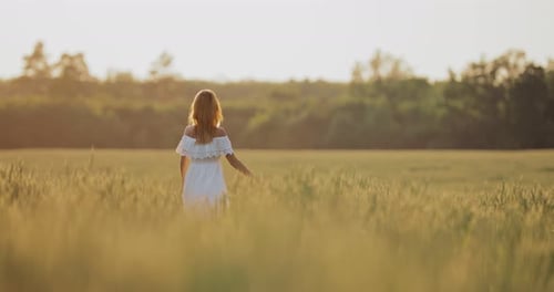 Young Woman Runs Through the Green Grass and Whirls in the Sun