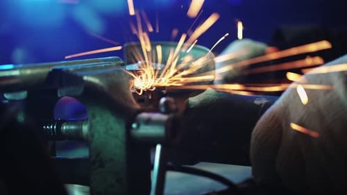 Un mecánico corta un tubo de metal con una amoladora