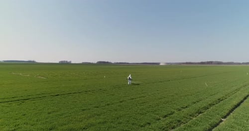 Agricultural Researcher Spraying Filed with Herbicides or Pesticides