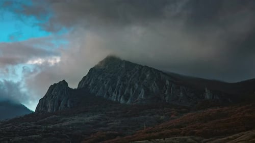 Un brouillard tourbillonnant en timelapse survole une chaîne de montagnes et s'accroche à son sommet