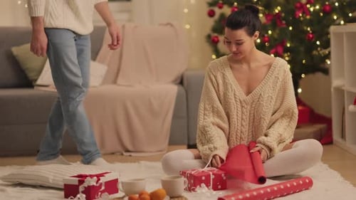 Couple Wrapping Christmas Gifts Together at Home