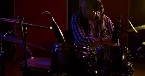 Man with dreadlocks playing drums in a music studio