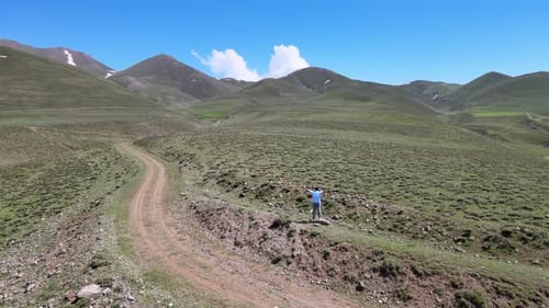 Adult Reaching for Mountains on Rural Hillside