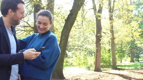 Friends Look at Smartphone in Sunny Park