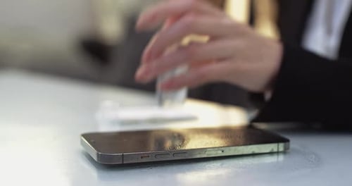 Woman Cleaning Cell Phone with Sanitizer at Desk