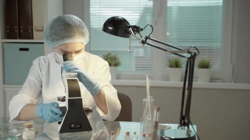 Young Adult Scientist Using a Microscope in Lab
