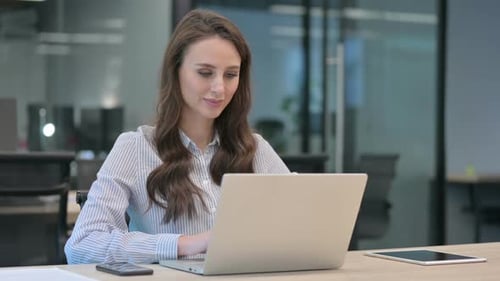 Woman Gives Thumbs Up While Working on Laptop