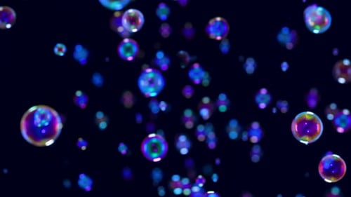 Blurred Footage of Beautiful Blue Rainbow Soap Bubbles Flying in the Air Against a Black Background