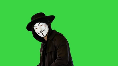 Hilarious Man Comic, der Schwertkampf und Tod nachahmt, trägt weiße Vendetta-Maske, schwarzer Trenchcoat und Hut