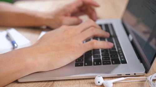 Hands Typing on Laptop Keyboard at Desk