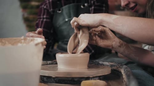 People Shaping Clay on a Pottery Wheel