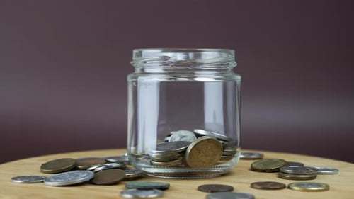 Coins Dropping Into Glass Jar Savings Concept