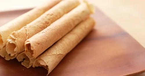 Crispy Rolled Wafers Stacked on Wooden Plate