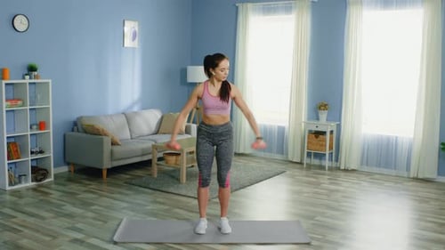 Young Woman Exercising Arms with Dumbbells at Home