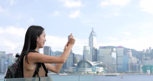 Young Woman taking photo with cellphone in Hong Kong Victoria harbor