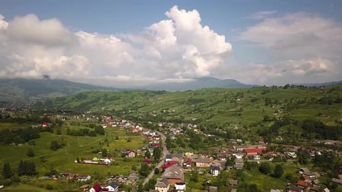 Aerial view of a small village between green summer hills in ukrainian Carpathian mountains