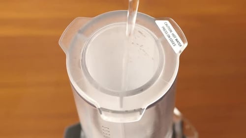 Water Being Poured into Clear Container