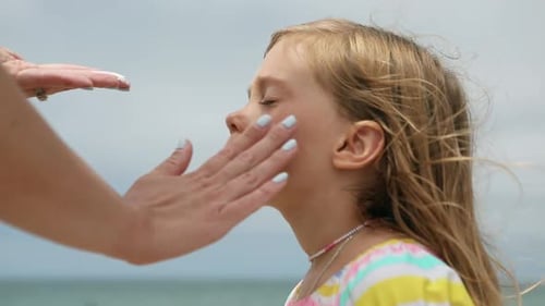Mother applying sunscreen on the face of her daughter