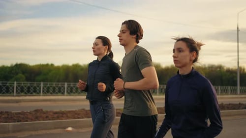 Athletic Persons are Running in Summer Morning Two Young Women and Man are Training Together