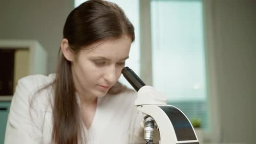 Woman Using Microscope in Brightly Lit Laboratory
