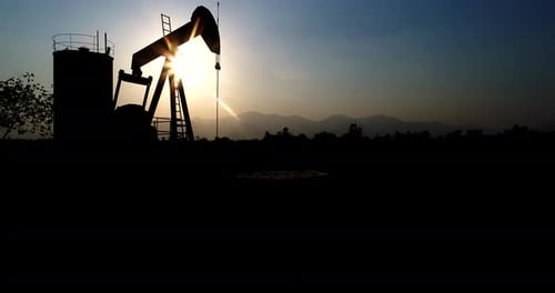 Industrial oil pump jack pumping crude oil for fossil fuel energy with drilling rig in oil field.