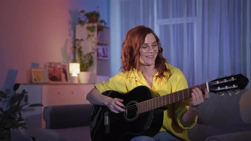 Woman Plays Guitar and Sings at Home