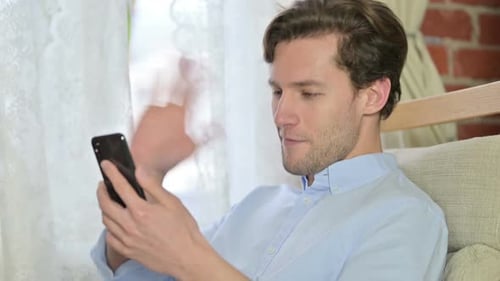 Young Adult Using Smartphone for Video Call Indoors