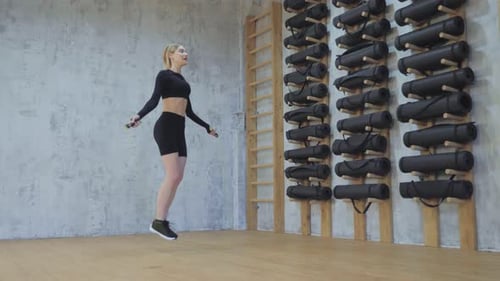 Woman Exercising with Jump Rope in Gym