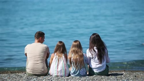 Family Enjoying Ocean View Sitting on Beach