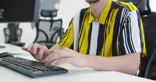Businessman Working at His Desktop Computer Sitting at His Desk in the Open Space Startup Office