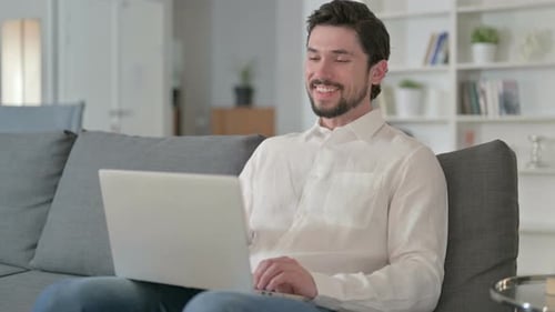 Man Waving During a Video Call on Laptop