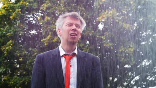 Man Stands in Heavy Rain Wearing a Suit