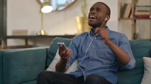 Young Man Listening to Music and Dancing Indoors