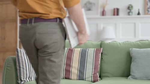 Young Man Opens Laptop on Sofa to Work