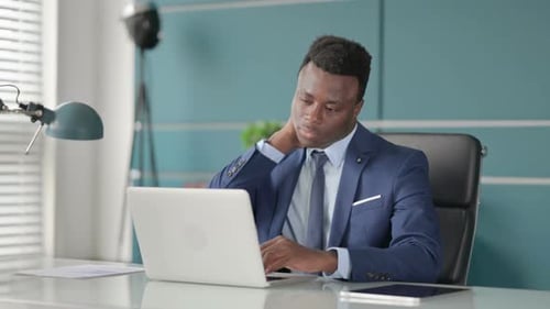 African Businessman Having Neck Pain While Using Laptop in Office