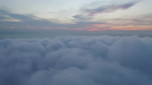 Aerial view of sunrise above fluffy sea fog misty clouds with mountain hill